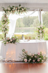 sweetheart table adorned with flowers under tent