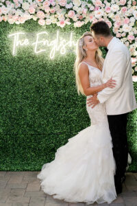newlyweds kissing in front of neon light backdrop wall