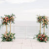colorful ceremony flowers on gold pedestals overlooking the ocean at Wave Resort