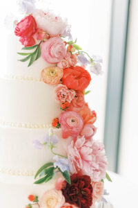 wedding cake with colorful flowers cascading down the tiers