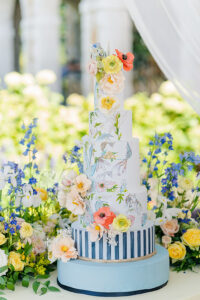 colorful wedding cake with blue pinstripes and hand painted flowers
