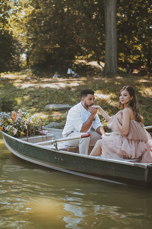 CWeddingsMag.com | groom-to-be kissing bride-to-be's hand in rowboat during engagement session in Central Park