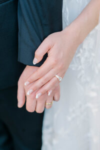 bride and groom showing off rings during portraits