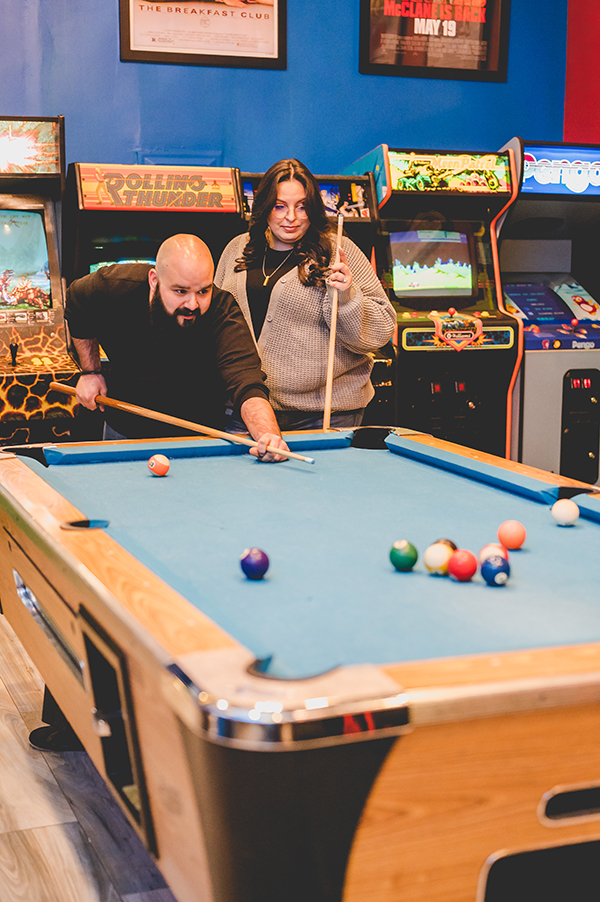 couple playing pool at Yestercades during engagement session