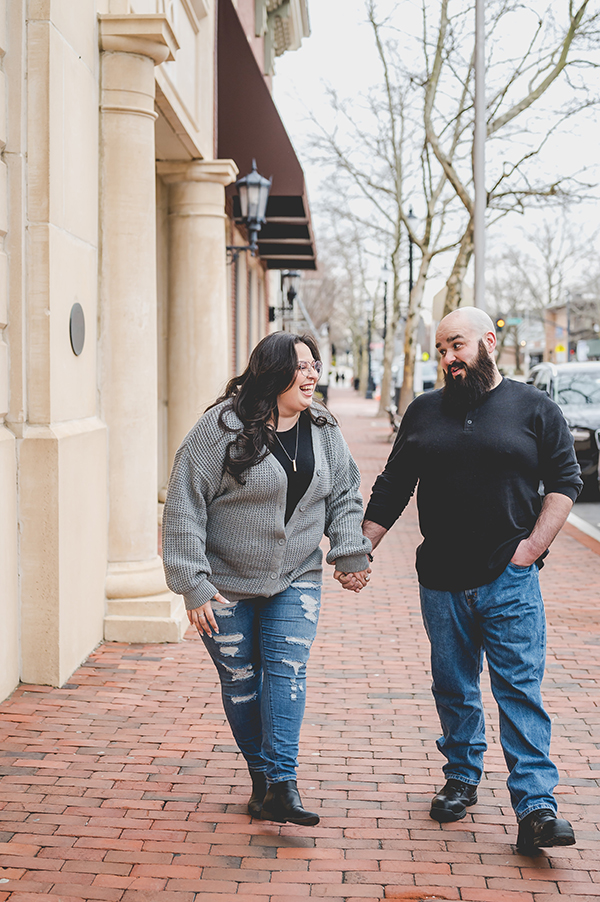 couple walking in downtown Red Bank laughing during engagement session