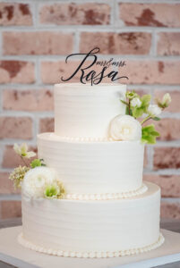 Classic white wedding cake with flowers and custom cake topper